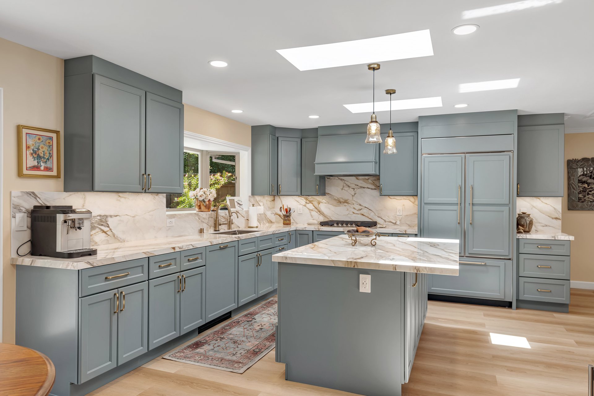 Sage green shaker kitchen with marble-look countertops, a center island and skylights
