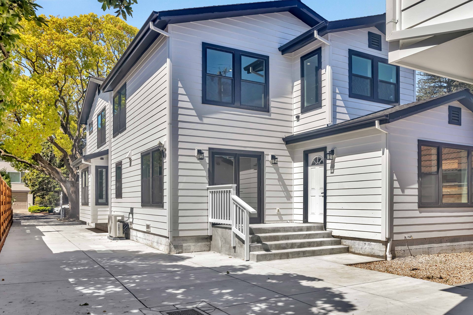 Two-story detached unit with white lap siding, black window frames and concrete entry steps